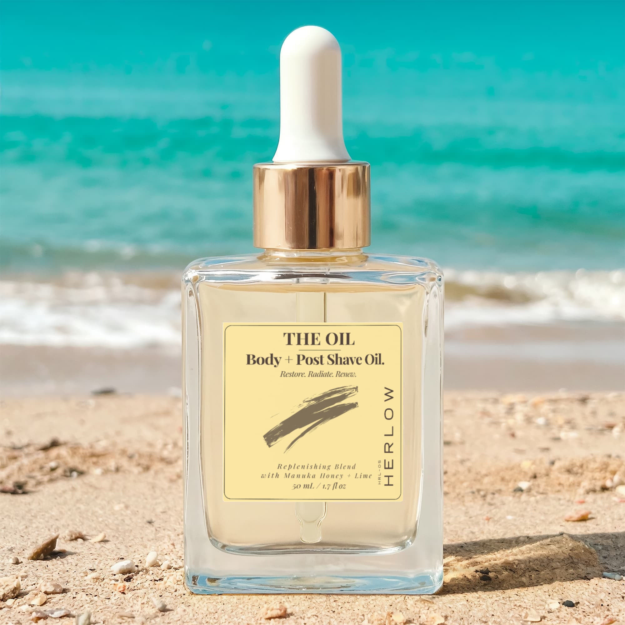 HERLOW Body and Post Shave Oil for women in clear bottle on sandy beach with ocean background