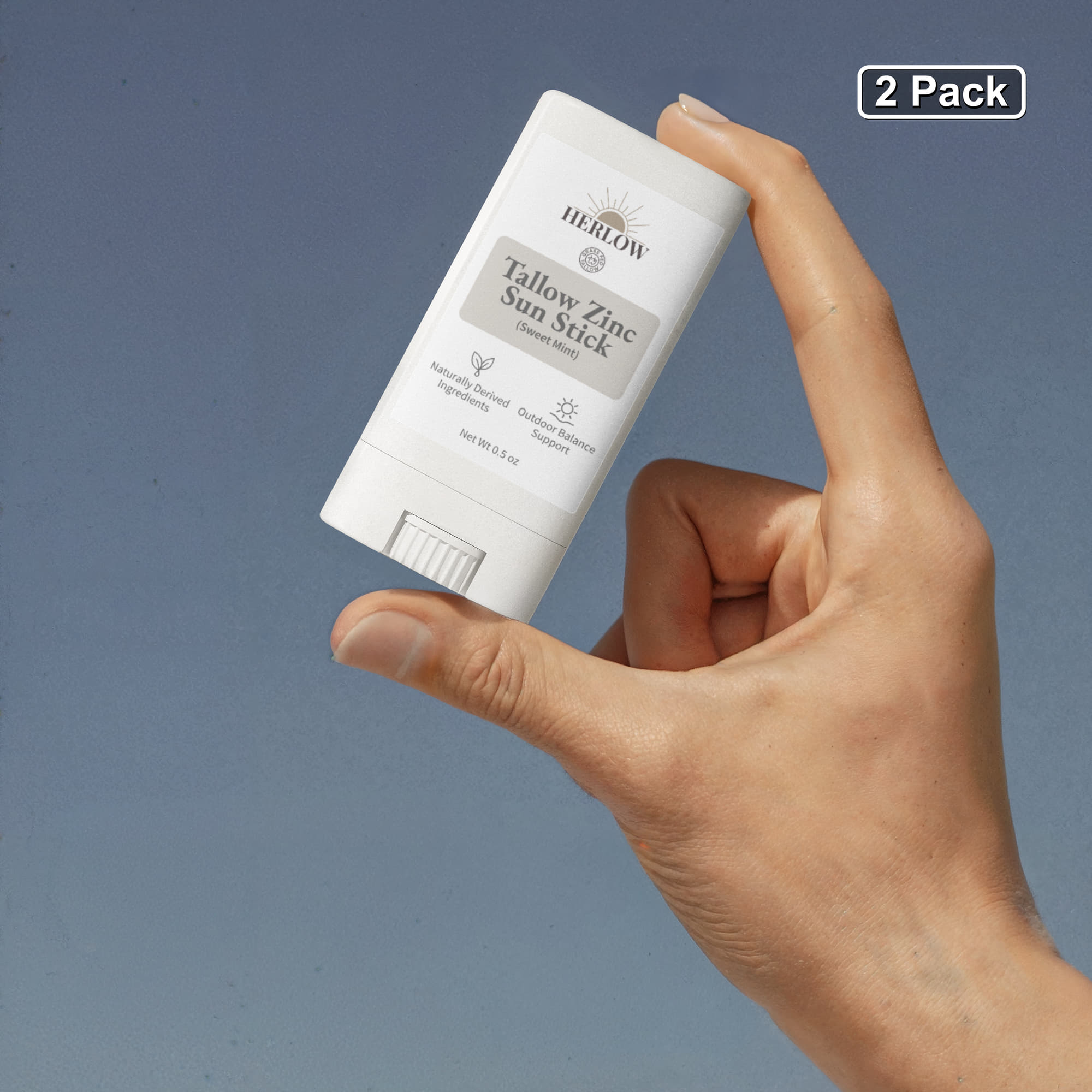 Hand holding a Tallow Sun Stick by HERLOW, ideal for sun protection in a convenient stick form
